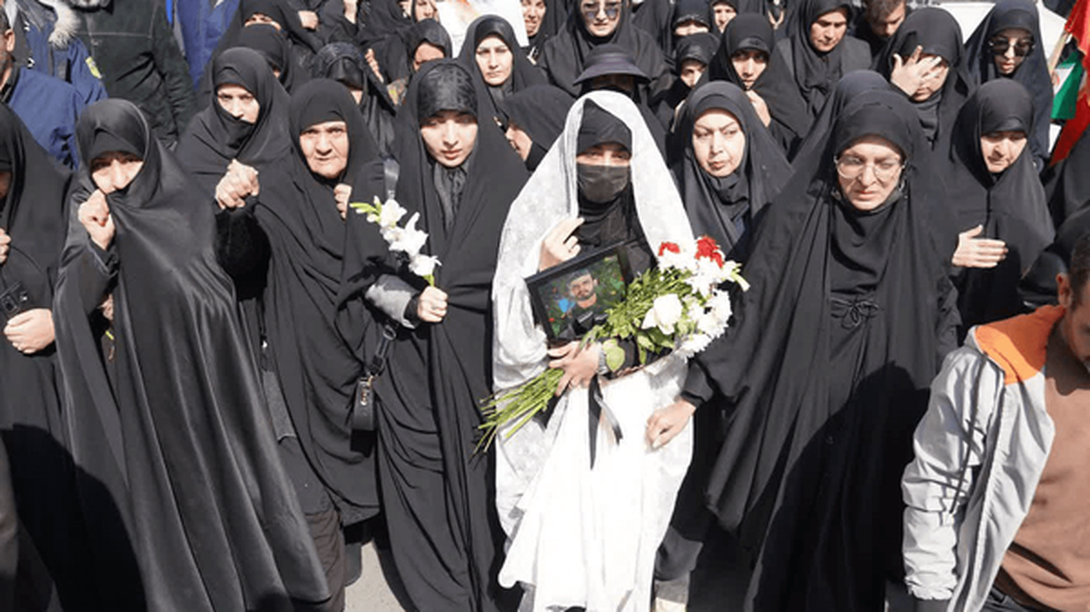 همسر شهید محمد نقوی با چادر سفید و گل به بدرقه همسرش آمد