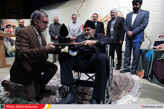 علی موسوی گرمارودی در حال اعطای لوح تقدیر به استاد سرویها