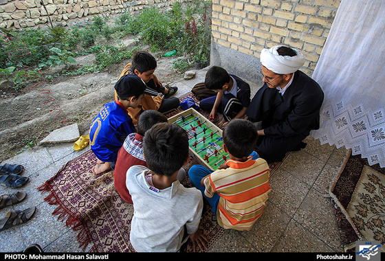 آقای بهادری در حال بازی فوتبال دستی با فرزند و دیگر کودکان روستا در خانه ی عالم
