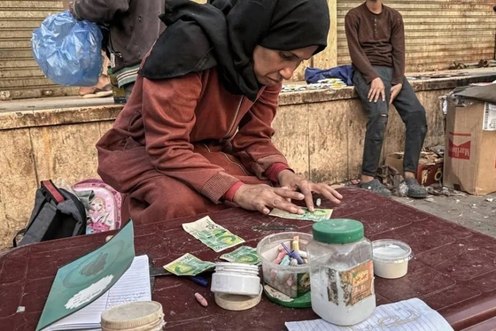 گزارش تصویری | زن فلسطینی با ترمیم اسکناس‌های پاره امرار معاش می‌کند