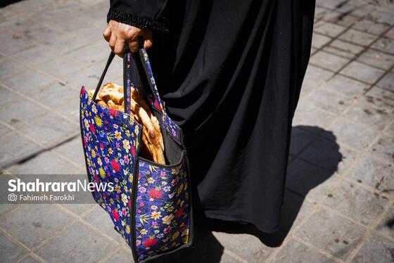 فرد نیازمند تعدادی نان از نانوایی تحویل گرفته است