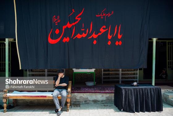  فردی در حال گوش دادن به روضه در حیاط حسینیه است
