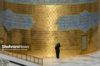 یکی از خدام در حال بوسیدن گنبد منور رضوی قبل از شروع آیین صلا می باشد