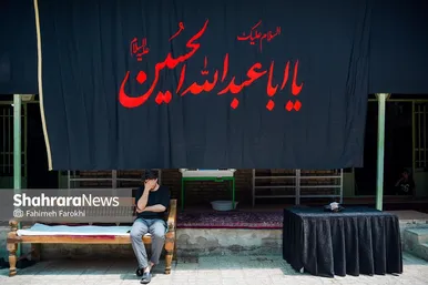  فردی در حال گوش دادن به روضه در حیاط حسینیه است
