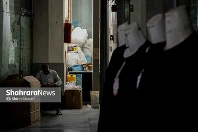 پیرمردی که دم در مغازه خود در تاریکی نشسته و چرت میزد 